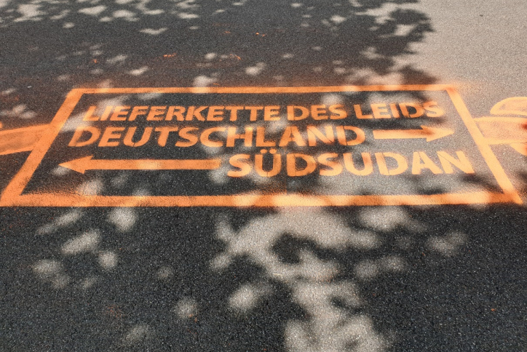 Wegweiser zeigen, wo die „Lieferkette des Leids" beginnt und endet.