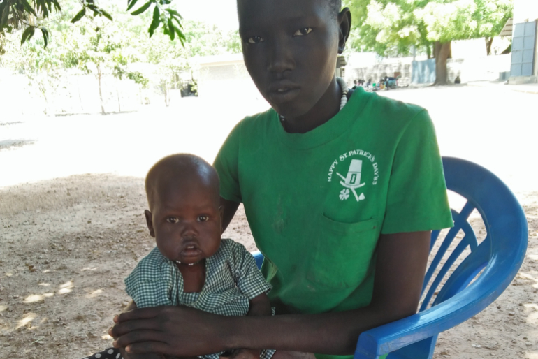 Beschützend hält die elfjährige Adeng Meen ihre kleine Schwester Amer auf dem Schoß. Ihre Mutter hat die Kinder nach dem Tod ihres Mannes aus Verzweiflung sich selbst überlassen.