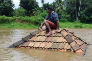 Ein Mann in Kerala rettet sich auf das Dach seines Hauses, das von den Fluten zerstört wurde.