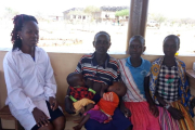 Gesundheitshelferin Catherine Aloko (links) nimmt sich Zeit für die Untersuchung der Zwillinge Esther und Rotich Daudi (Mitte). Der Zustand der Kinder ist ernst. Im Hintergrund ist der Rohbau des zentralen Klinikgebäudes in Kosike zu sehen.